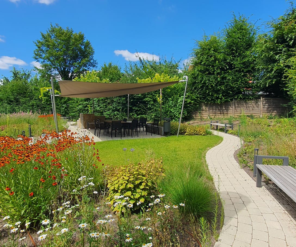 Sommerlicher Garten eines Büros, ausgestattet mit Sonnenschutz und einer Terrasse.