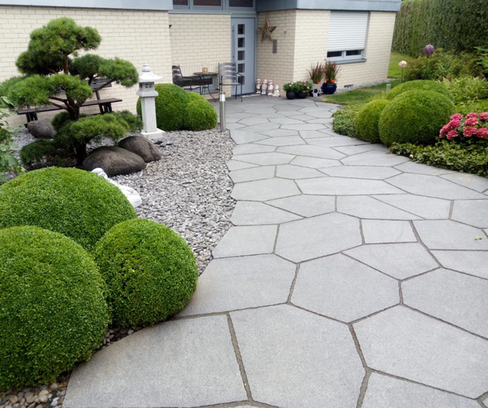 Steinernen Weg, der durch einen Garten führt und auf ein Haus zuläuft.