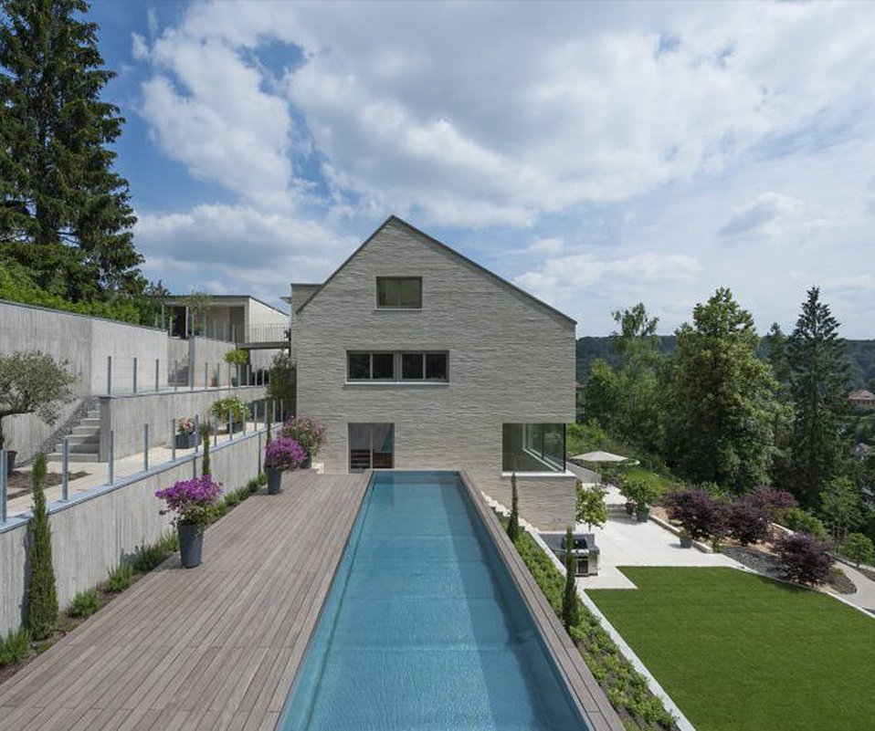 Haus mit einem großen rechteckigen Pool. Auf der linken Seite des Pools befindet sich eine Terrasse, die zum Entspannen und Genießen des Außenbereichs einlädt.