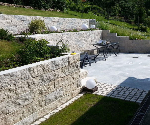 Von Steinen eingefasste Terrasse mit Gartenmöbeln.