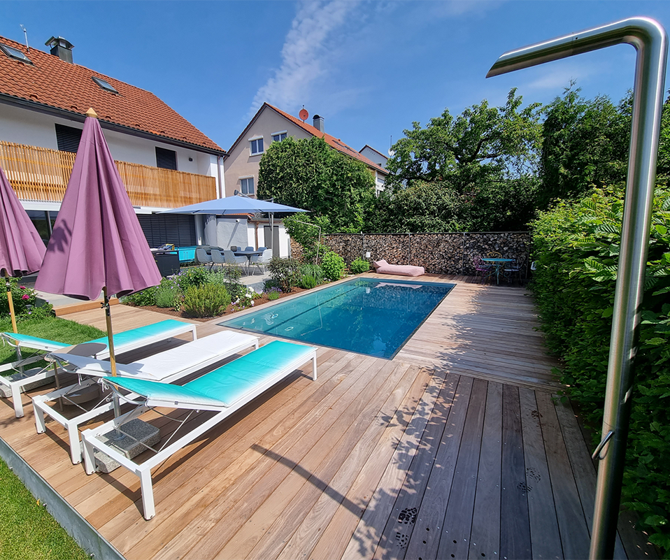 Zwei blaue Liegen vor einem Pool im Sommer.